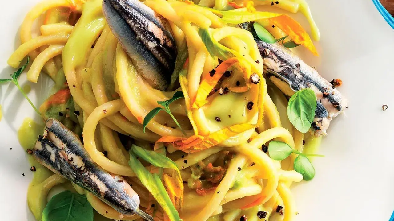 Pasta con fiori di zucca e alici, un piatto estivo colorato e saporito, con erbe fresche e pepe nero.