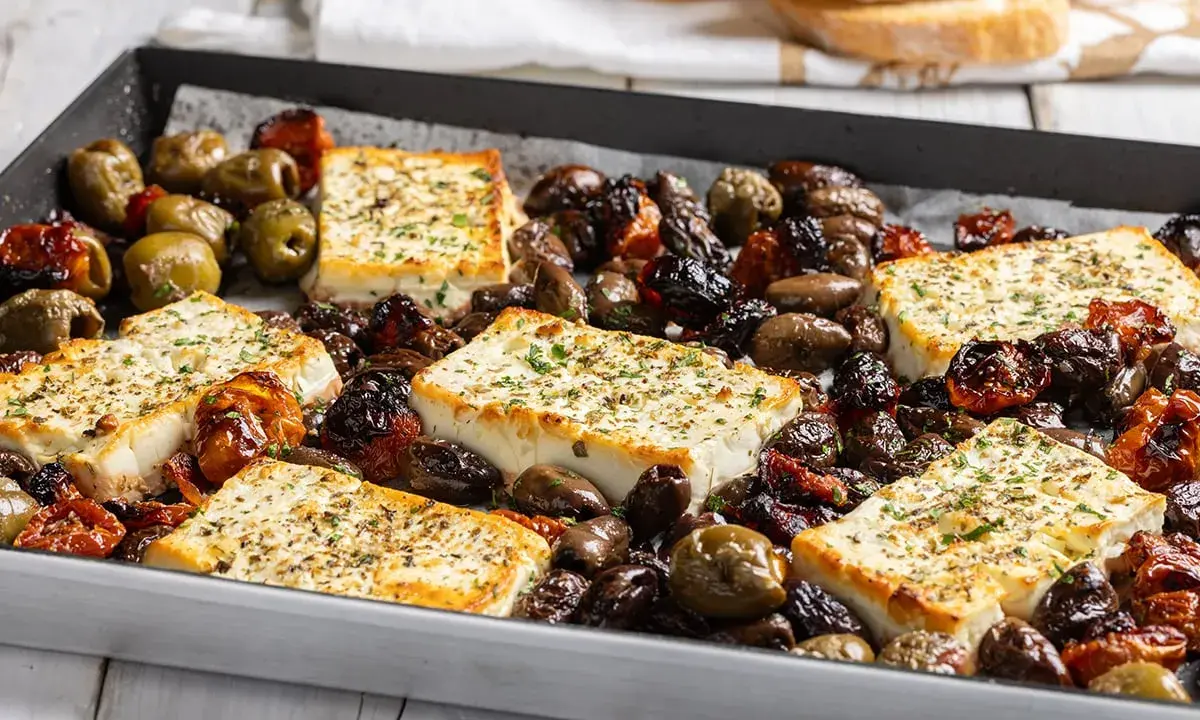 Feta al forno con olive e pomodorini secchi, un piatto saporito e profumato, pronto per essere gustato.