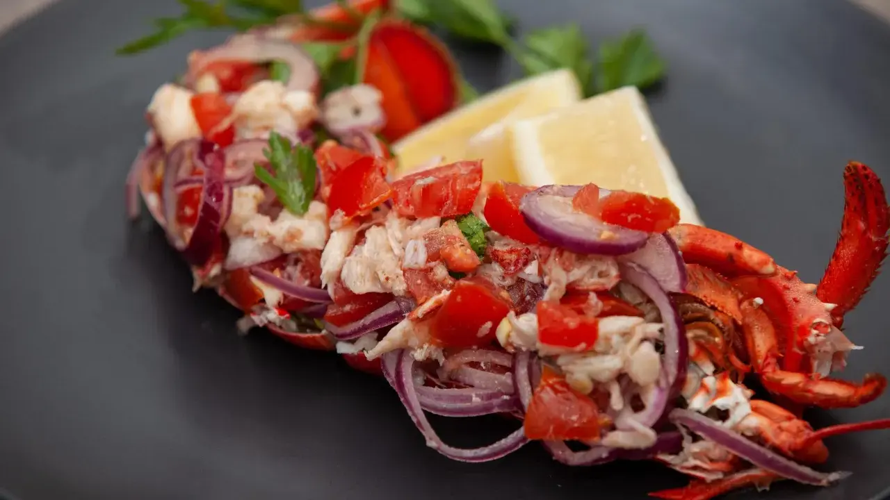 Astice alla catalana: polpa di astice sfilacciata con pomodoro, cipolla rossa e limone, guarnito con prezzemolo.