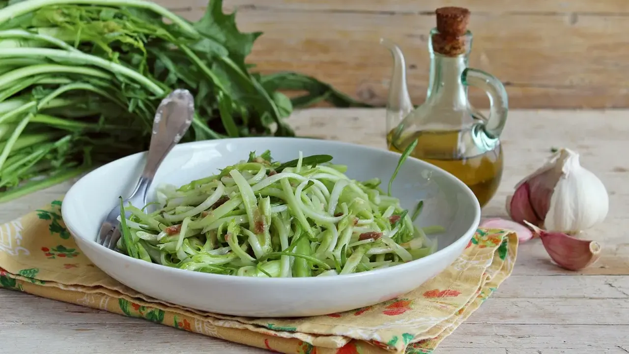Un piatto di puntarelle alla romana, condite con olio e aglio, pronte per essere gustate.