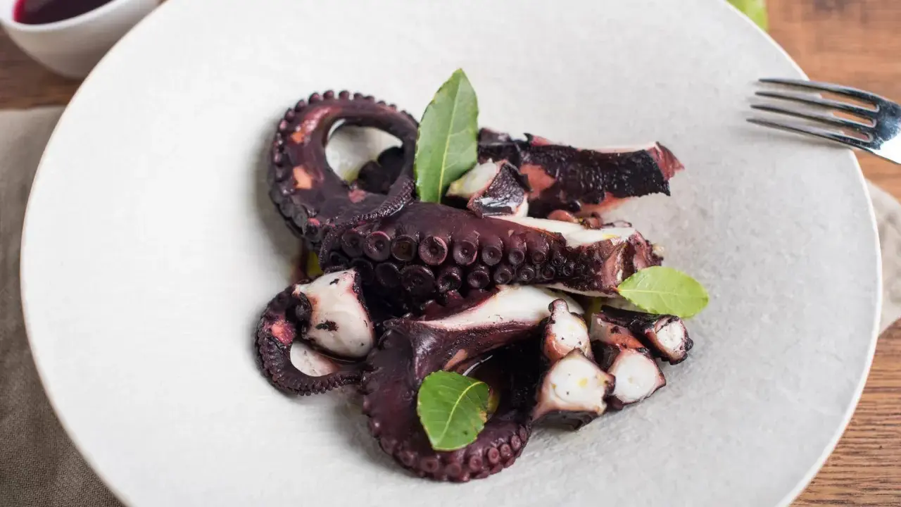 Polpo ubriaco ricetta: tentacoli succulenti e profumati, cotti a puntino e guarniti con foglie di alloro.