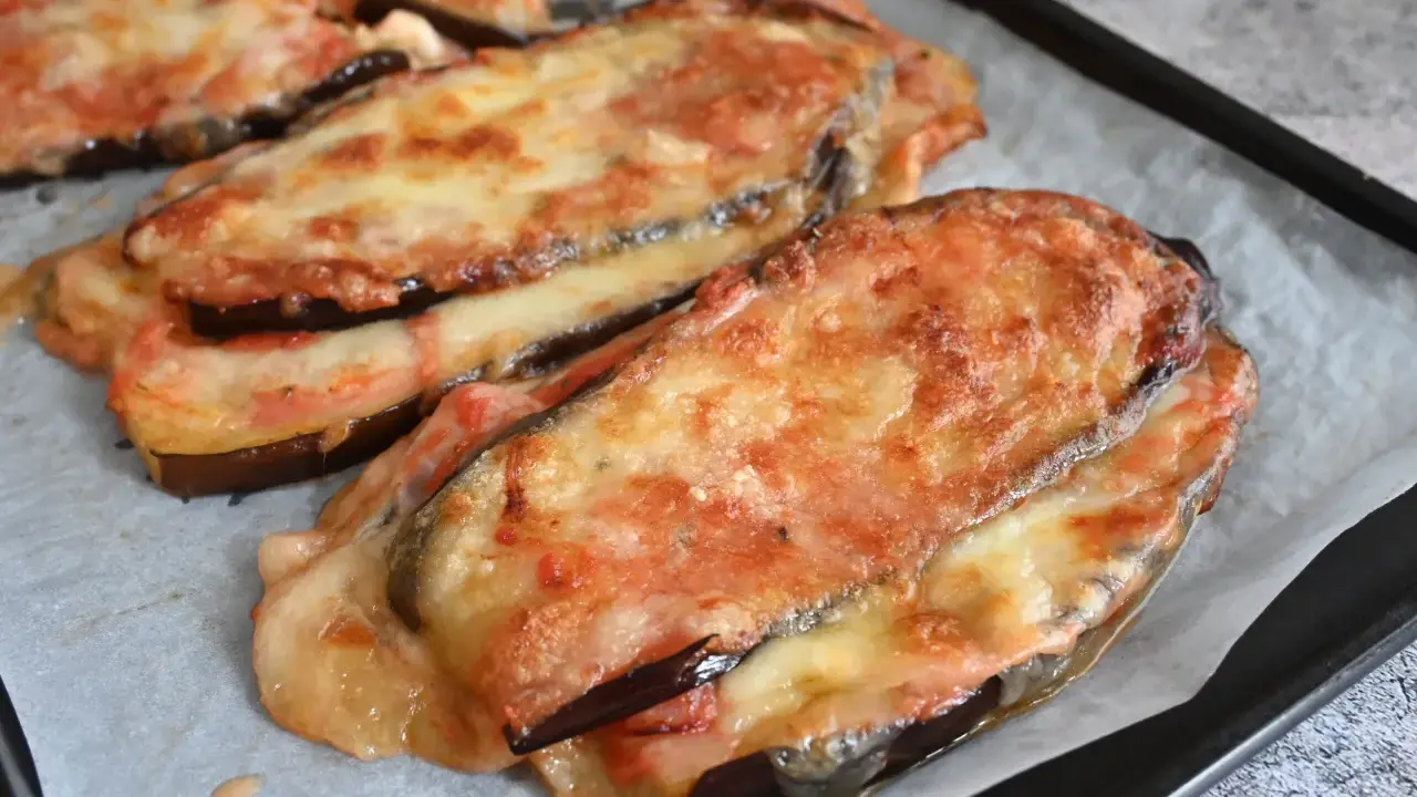 Melanzane al forno gratinate con formaggio filante e pomodoro, pronte per essere gustate.