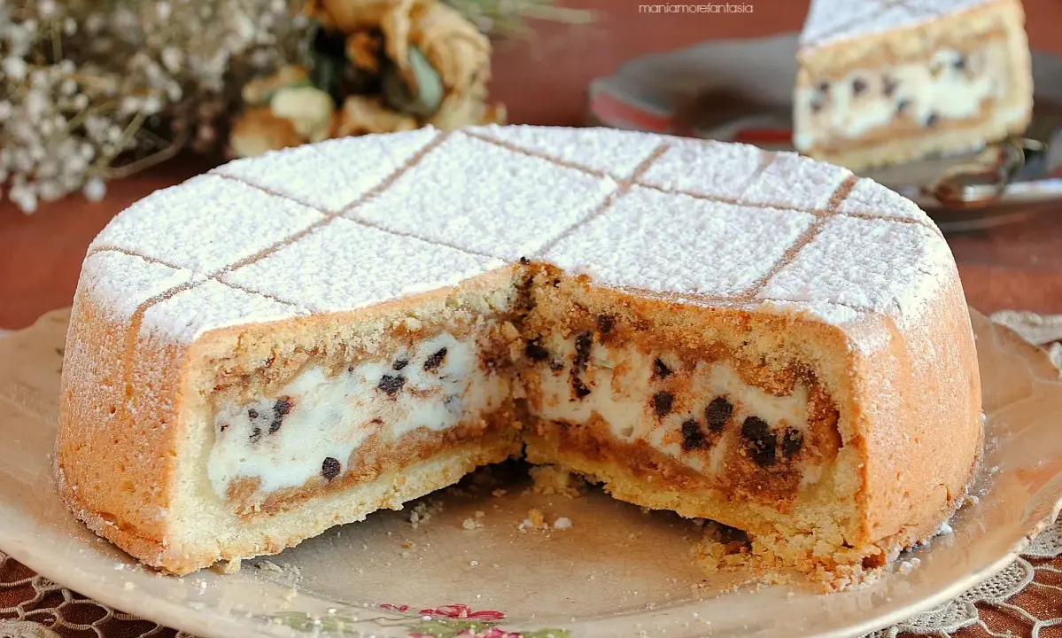 Una fetta di cassata al forno, con la sua crema vellutata e gocce di cioccolato, spolverata di zucchero a velo.