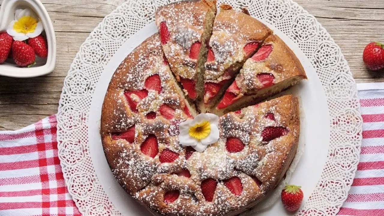 Torta di fragole e yogurt, soffice e profumata, cosparsa di zucchero a velo e decorata con un fiore. Perfetta per una colazione o merenda.