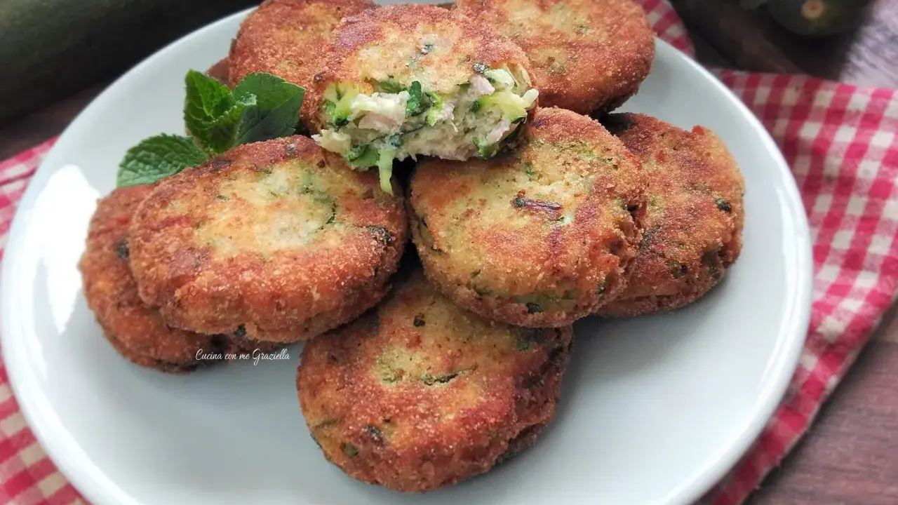 Piatto di polpette di zucchine e ricotta dorate e croccanti, guarnite con menta fresca.