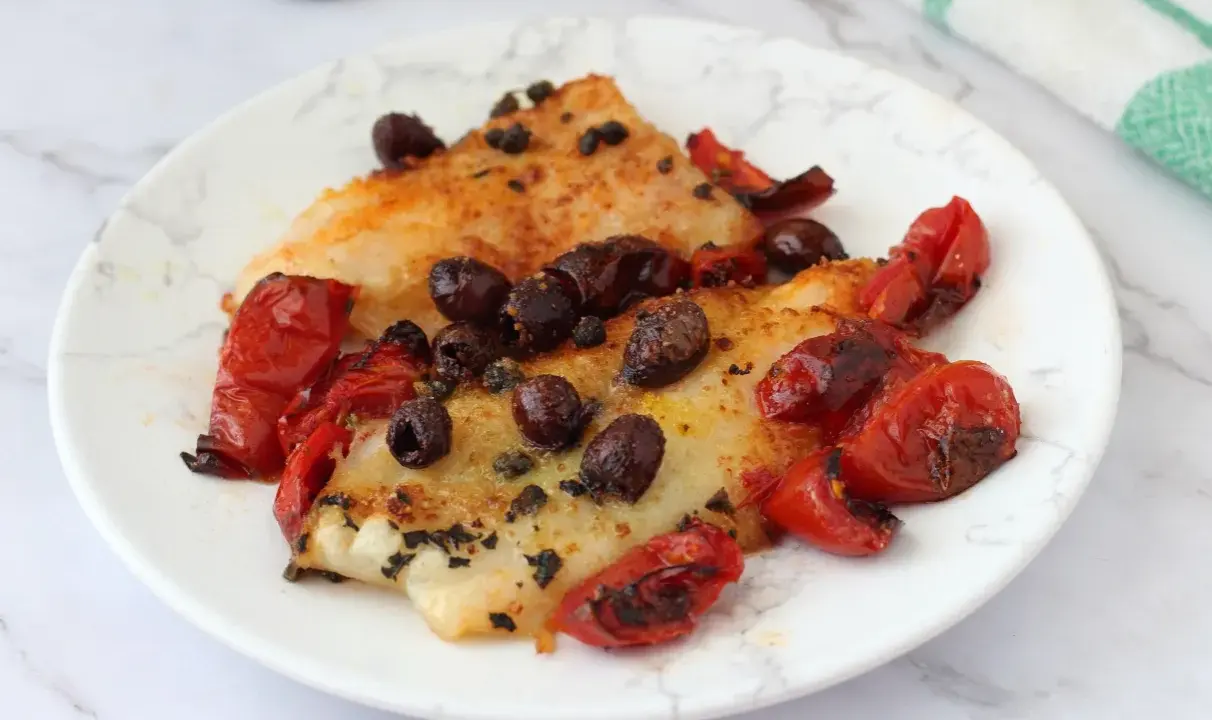 Delizioso merluzzo in friggitrice ad aria, condito con pomodorini e olive nere. Un piatto leggero e saporito.
