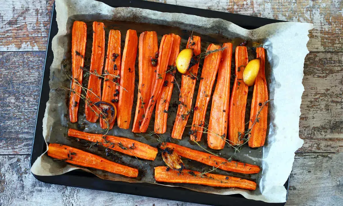 Carote al forno dorate e caramellate, condite con erbe aromatiche, pepe nero e spicchi d'aglio. Un contorno semplice e gustoso.
