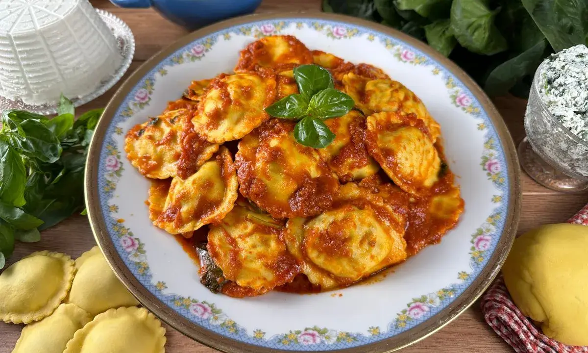 Piatto di ravioli ricotta e spinaci conditi con sugo rosso e basilico fresco. Ingredienti freschi e pasta fatta in casa.