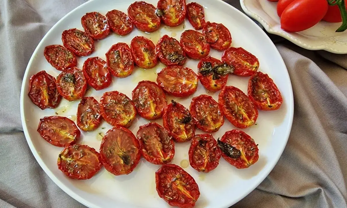 Pomodorini al forno, dorati e succosi, conditi con erbe aromatiche, pronti per insaporire ogni piatto.