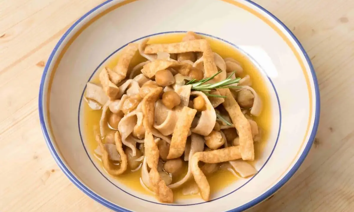 Piatto di ciceri e tria, pasta fresca con ceci e sfoglie fritte, guarnito con rosmarino.