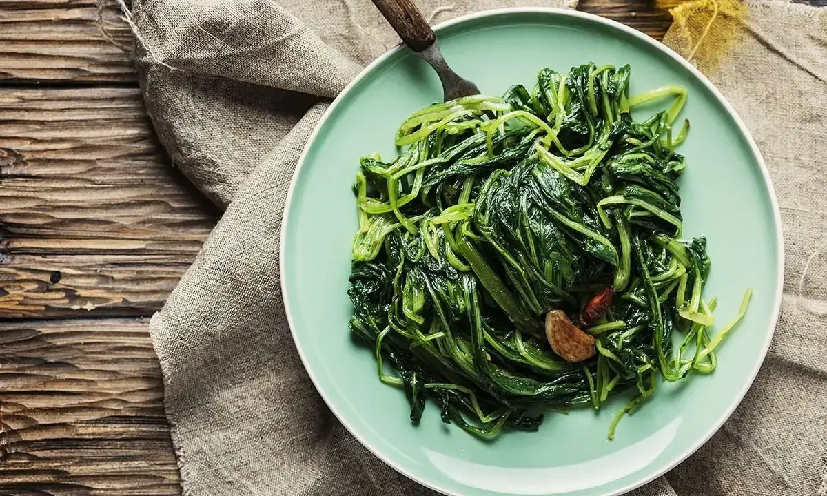 Piatto di puntarelle in padella, condite con aglio e peperoncino, pronte per essere gustate.