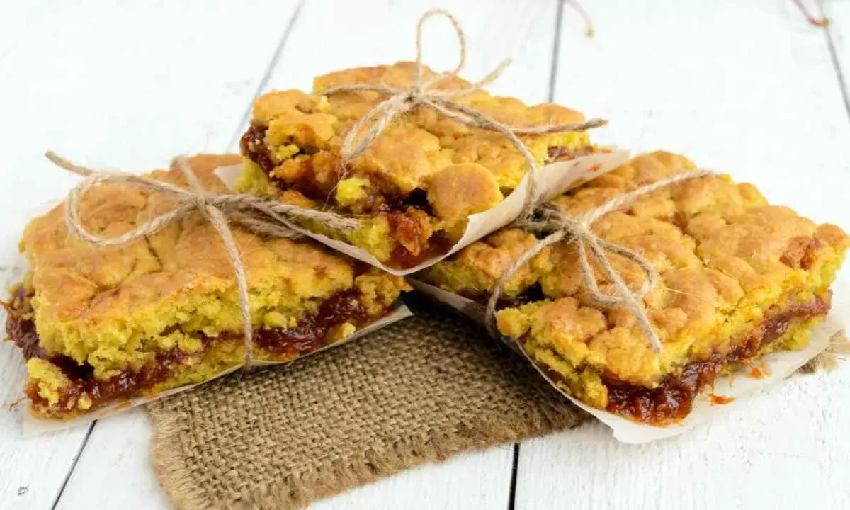 Tre fette di torta con marmellata, legate con spago, su carta da forno e tela di juta.