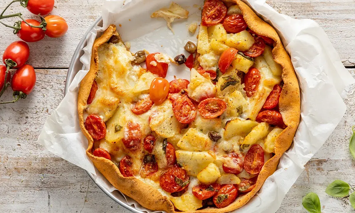 Torta salata con patate, pomodorini e formaggio filante, un piatto rustico e gustoso, pronto per essere gustato.