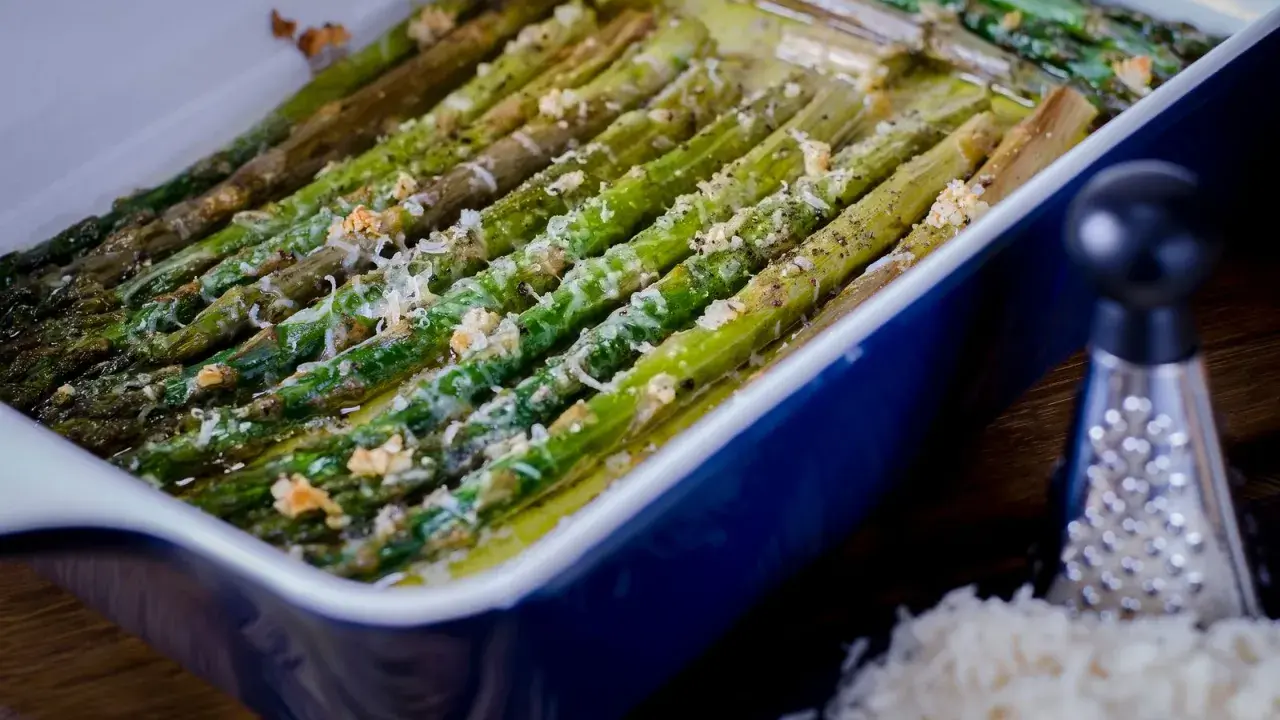 Asparagi al forno dorati e saporiti, conditi con formaggio grattugiato e pepe nero, pronti per essere gustati.
