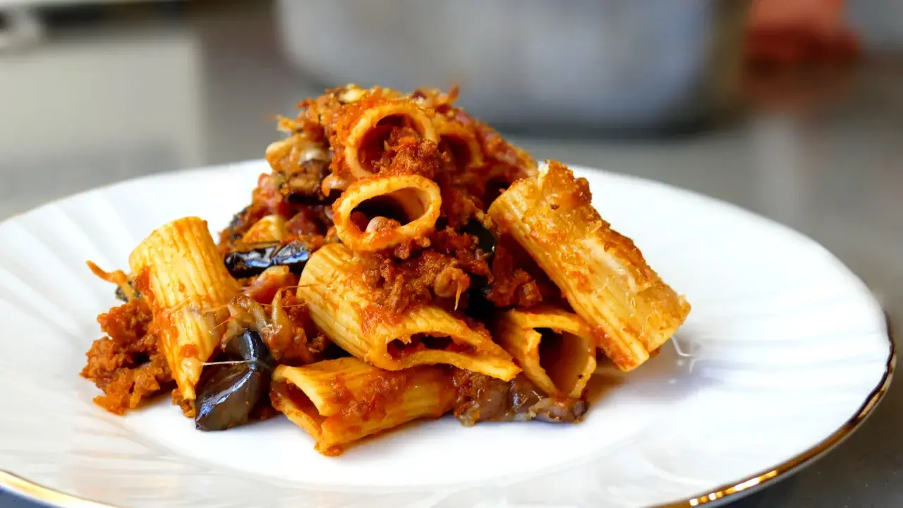 Piatto di pasta e melanzane alla napoletana, con rigatoni ricchi di sugo e melanzane fritte.