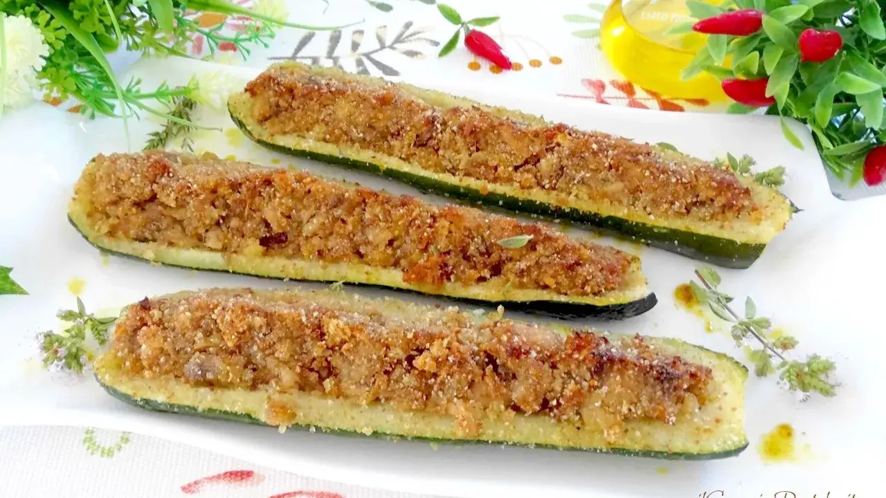 Zucchine ripiene tonno, dorate e croccanti, servite su un piatto bianco con erbe aromatiche.