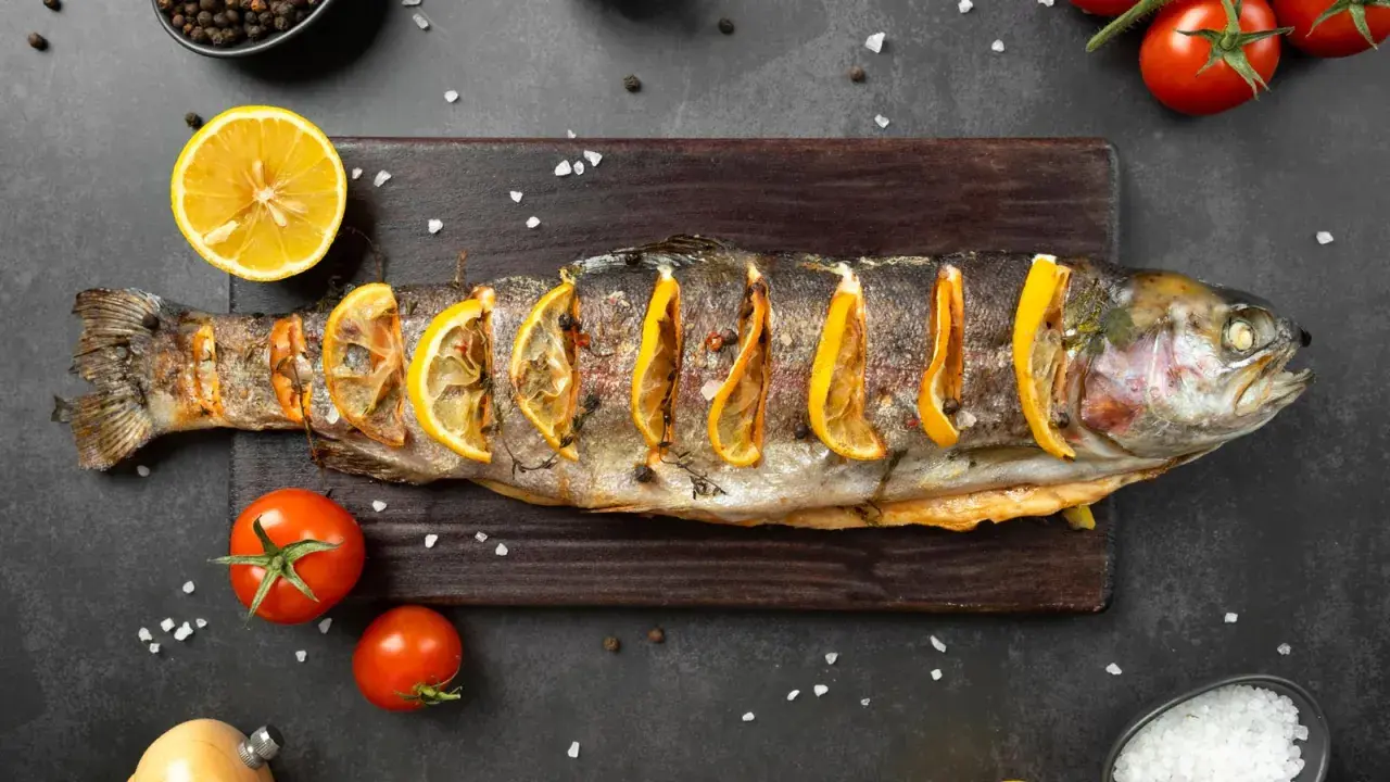 Un succulento pesce alla brace, guarnito con fette di limone e erbe aromatiche, pronto per essere gustato.