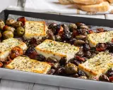 Feta al forno con olive e pomodorini secchi, un piatto saporito e profumato, pronto per essere gustato.