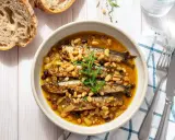 Sarde in saor, un piatto veneziano con sarde, cipolle, pinoli e uvetta, servito in una ciotola con pane rustico.