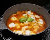 Patate alla pizzaiola in padella, con mozzarella filante e basilico fresco. Un piatto gustoso e invitante.