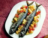Due filetti di sgombro al forno, cotti alla perfezione, serviti con patate e carote a cubetti su un piatto bianco.