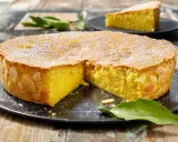 Deliziosa caprese al limone, con mandorle tostate sui bordi e scorzetta d'arancia in superficie, cosparsa di zucchero a velo.