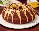 Ciambella al caffè, ricoperta da glassa caramello e gocce di cioccolato, pronta per essere gustata.