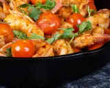 Gamberoni in padella succulenti, cotti con pomodorini e profumati aromi, pronti per essere gustati.