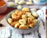 Gnocchi dorati e croccanti in friggitrice ad aria, serviti in una ciotola su carta di giornale.