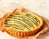 Torta salata asparagi con crosta dorata e ripieno cremoso, decorata con asparagi freschi disposti a raggiera.