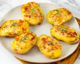 Patate ripiene al forno, dorate e gratinate, guarnite con rosmarino fresco. Un piatto invitante e saporito.