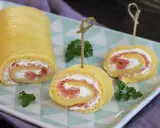 Rotolo di frittata ripieno di salmone affumicato e formaggio cremoso, guarnito con prezzemolo. Un antipasto elegante e gustoso.