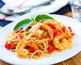 Un piatto invitante di spaghetti con gamberetti succulenti e pomodorini freschi, guarnito con basilico.