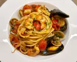 Un invitante piatto di spaghetti allo scoglio, con gamberi, cozze, vongole e calamari, condito con pomodorini e prezzemolo.