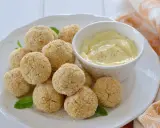 Polpette di ceci al forno dorate e croccanti, servite su un piatto bianco con una ciotolina di salsa cremosa e foglie di menta.