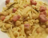 Un piatto di pasta e ceci in scatola, arricchito da cubetti di pancetta e un rametto di rosmarino.