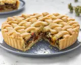 Una crostata morbida salata con verdure miste, peperoni e melanzane, ricoperta da una griglia di pasta dorata.