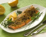 Deliziosa trota salmonata al forno, croccante e profumata, servita con limone e erbe aromatiche fresche.