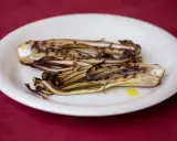 Radicchio in padella, grigliato e caramellato, servito su un piatto bianco con un filo d'olio.