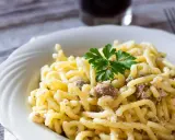 Piatto di pasta con salsiccia sbriciolata, condita con un sugo cremoso e guarnita con prezzemolo fresco.