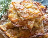 Schiacciata di patate croccante, dorata e invitante, con fette sottili di patate e un tocco di rosmarino.