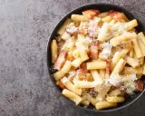 Un piatto di pasta alla zozzona fumante, con guanciale croccante e abbondante pecorino grattugiato, pronto per essere gustato.