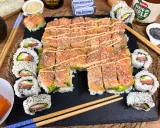 Un invitante sushi fatto in casa con salmone e avocado, guarnito con semi di sesamo e una salsa cremosa.