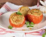 Tre pomodori gratinati al forno, ripieni e dorati, guarniti con prezzemolo fresco su un piatto bianco.