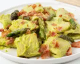 Piatto di pasta con crema di asparagi, punte di asparagi freschi e croccante speck.