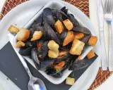 Un invitante piatto di impepata di cozze, ricco di molluschi neri e crostini dorati, pronto per essere gustato.