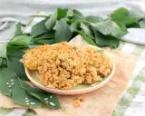 Piatto di fiori di sambuco fritti, dorati e croccanti, guarniti con sale e accompagnati da foglie verdi e piccoli fiori bianchi.