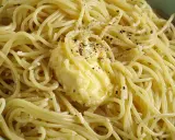 Un piatto di spaghetti fumanti, conditi con burro fuso e pepe nero macinato fresco, un classico cacio e pepe pronto da gustare.