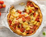 Torta salata con patate, pomodorini e formaggio filante, un piatto rustico e gustoso, pronto per essere gustato.