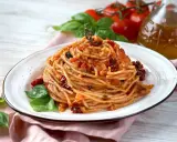 Spaghetti con pomodori secchi, basilico fresco e un filo d'olio d'oliva. Un piatto semplice e gustoso, pronto per essere assaporato.
